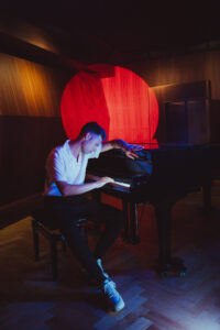 Henri Louis am Klavier in rotem und blauem Licht
